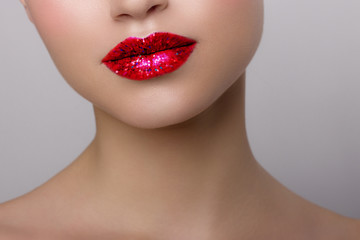 Obraz premium Close-up of woman's lips with bright fashion red glossy makeup. Macro bloody lipgloss make-up