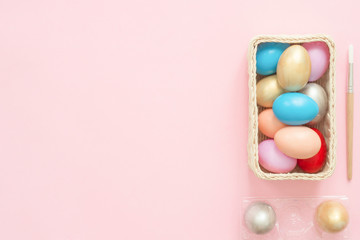 Flat lay top view colorful easter egg painted in pastel colors composition with paint brush on pink pastel color background. Easter day background top view with copy space.