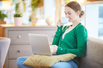 Young woman working at home with laptop and coffee