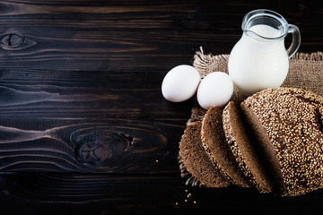 Freshly baked homemade bread with milk and eggs on a black background.