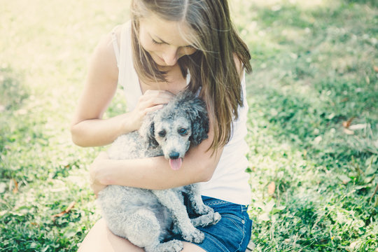 Young Woman Hugging  Her Dog In The Park.