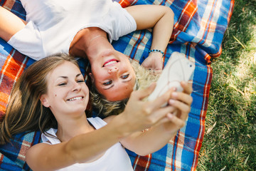 Three happy friends  taking selfie with smartphone  and having fun while lying on the grass in garden.