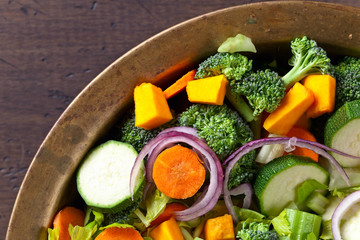 Sliced fresh raw vegetables on old wooden table .