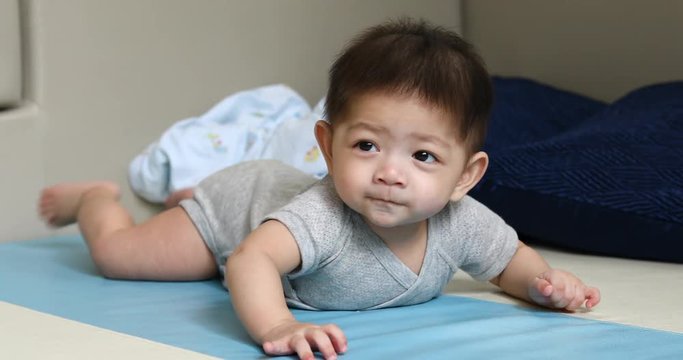 cute asian baby boy trying crawl on soft floor in nursery room