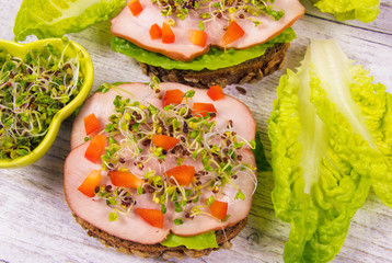 Sandwiches with lettuce, ham and broccoli sprouts.