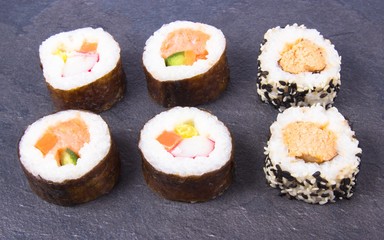 Various kinds of sushi on the dark background.