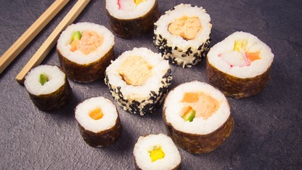 Various kinds of sushi on the dark background.