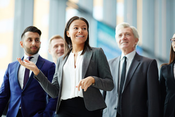 Young businesswoman or guide showing group of delegates interior of new building