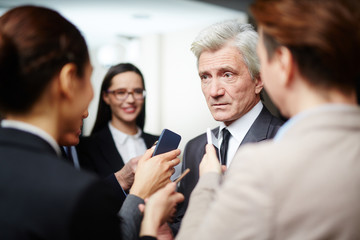Confident politician in suit asking questions of journalists during press conference