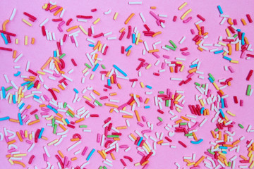 Multicolored confetti on a pink background top view