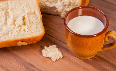 steaming fresh bread mug with milk on a wooden background