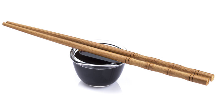 Soy sauce and bamboo chopsticks on white background