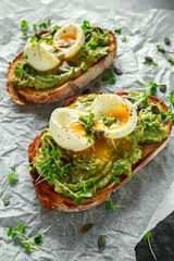 Healthy avocado and egg toasts with pumpkin and sesame seeds, sprinkled with cress salad