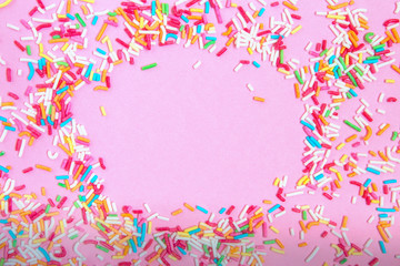 Multicolored confetti on a pink background top view