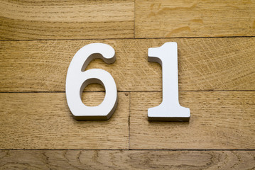 The numbers sixty-one on the wooden parquet floor.