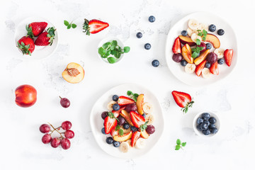 Fruit salad with strawberry, blueberry, peach, banana, grape and fresh fruits on white background. Flat lay, top view