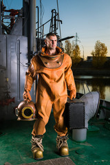 Fototapeta na wymiar A brave diver in retro gear is standing on the deck of a ship