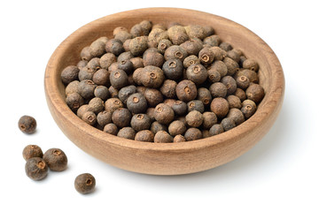 dried herb, allspice in the wooden plate. isolated on white