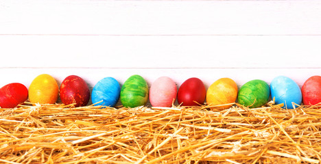 Row of  colorful Easter eggs on white  wood background -  Rustic spring holiday banner with traditional  symbolic food and horizontal copy space