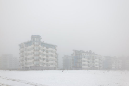 Mystical landscape of residential low-rise houses in dense fog