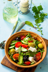 Summer vitamin salad. Greek salad with fresh vegetables, feta cheese and black olives on a blue stone or concrete table. Diet, concept of vegetarian food.