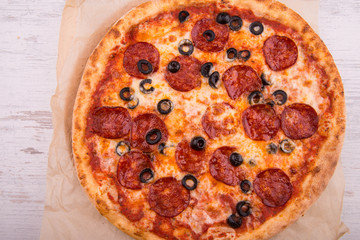 Pizza with pieces of salami and black olives
