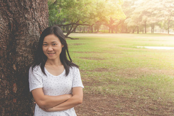 Vacation and Holiday Concept : Woman wearing white t-shirt. She standing on green grass and feeling relax and happiness in the park.