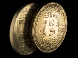 two Golden bitcoins on a black background, closeup. electronic money
