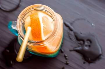 water with orange and lemon in a glass jar on a dark background. concept vitamins and health