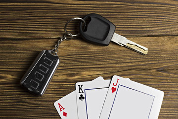 Playing cards and car keys on a wooden background