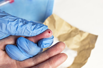 .A doctor takes blood from a finger, close-up