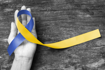 World down syndrome day WDSD March 21 Blue yellow awareness ribbon on helping hand for raising support on patient with down syndrome illness disability and Thoracic Outlet Syndrome - (TOS)