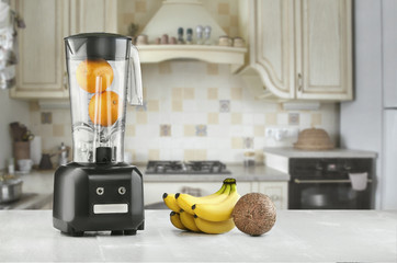 Metal food blender close-up with fresh exotic tropic fruits next to it on kitchen background with...