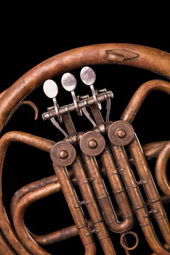 Vintage bronze pipes, valve, key mechanical elements french horn, black background. Good pattern, prompt music instrument.