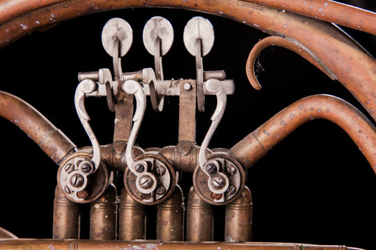 Vintage bronze pipes, valve, key mechanical elements french horn, black background. Good pattern, prompt music instrument.