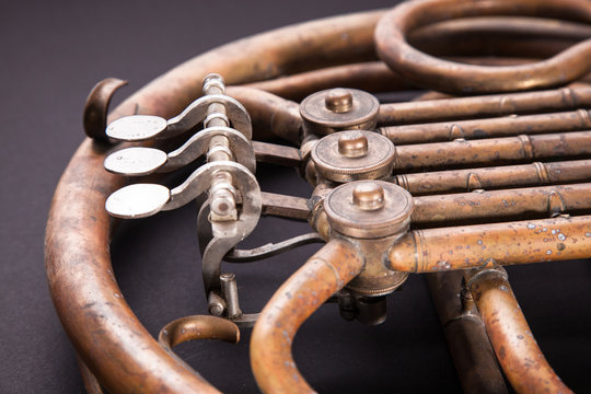Vintage bronze pipes, valve, key mechanical elements french horn, black background. Good pattern, prompt music instrument.