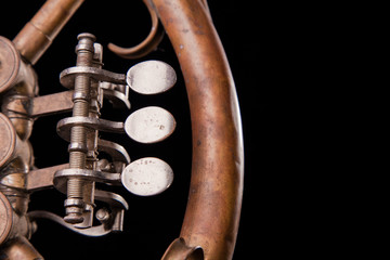 Vintage bronze pipes, valve, key mechanical elements french horn on black isolated background. Good pattern, prompt music instrument.