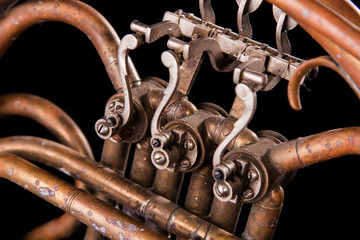 Vintage bronze pipes, valve, key mechanical elements french horn, black background. Good pattern,...