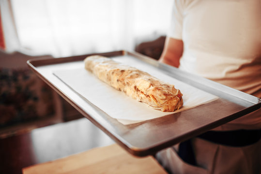 Chef holds metal baking sheet with apple strudel