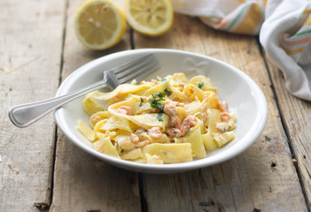 Homemade italian pasta with smoked salmone and creamy sauce and parsley on the top, white plate on the wooden rustic table