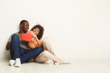 Fototapeta na wymiar Happy african-american couple holding paper heart