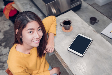Fototapeta na wymiar Asian woman using tablet on cafe counter bar with coffee cup and smile emotion,leisure lifestyle concept.