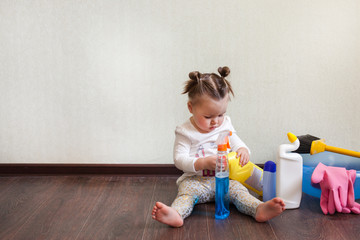 child playing with bottles with household chemicals sitting on the floor of the house