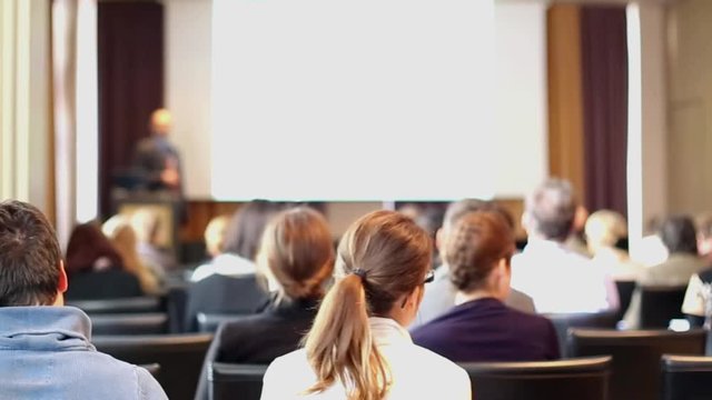 Speaker giving a talk on corporate business event. Rear view of unrecognized people in audience at conference hall. Business and Entrepreneurship event.