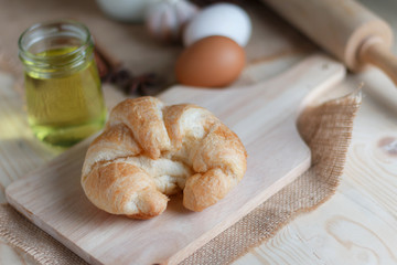 Croissant on wooden cut board on table wood and fabric select focus shallow depth of field
