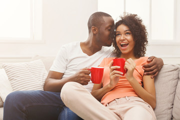 Obraz na płótnie Canvas Smiling black couple drinking coffee at home