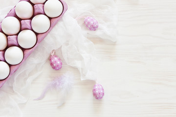 Top view of white eggs and pink colored Easter eggs r on white wooden background. Top view, Easter concept, greeting card