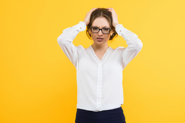 Portrait of confident beautiful young business woman holding head with her hands on yellow background