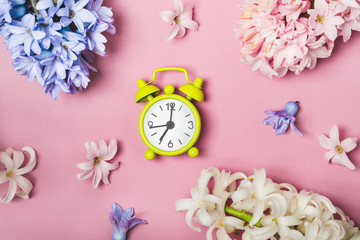 Spring flowers pink flat lay. Alarm clock. Springtime concept