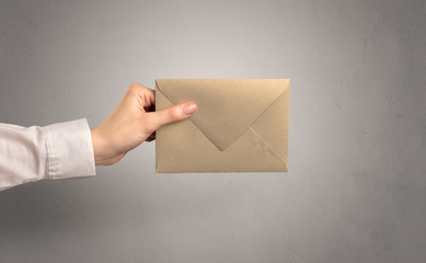 Hand holding envelope with empty wall background